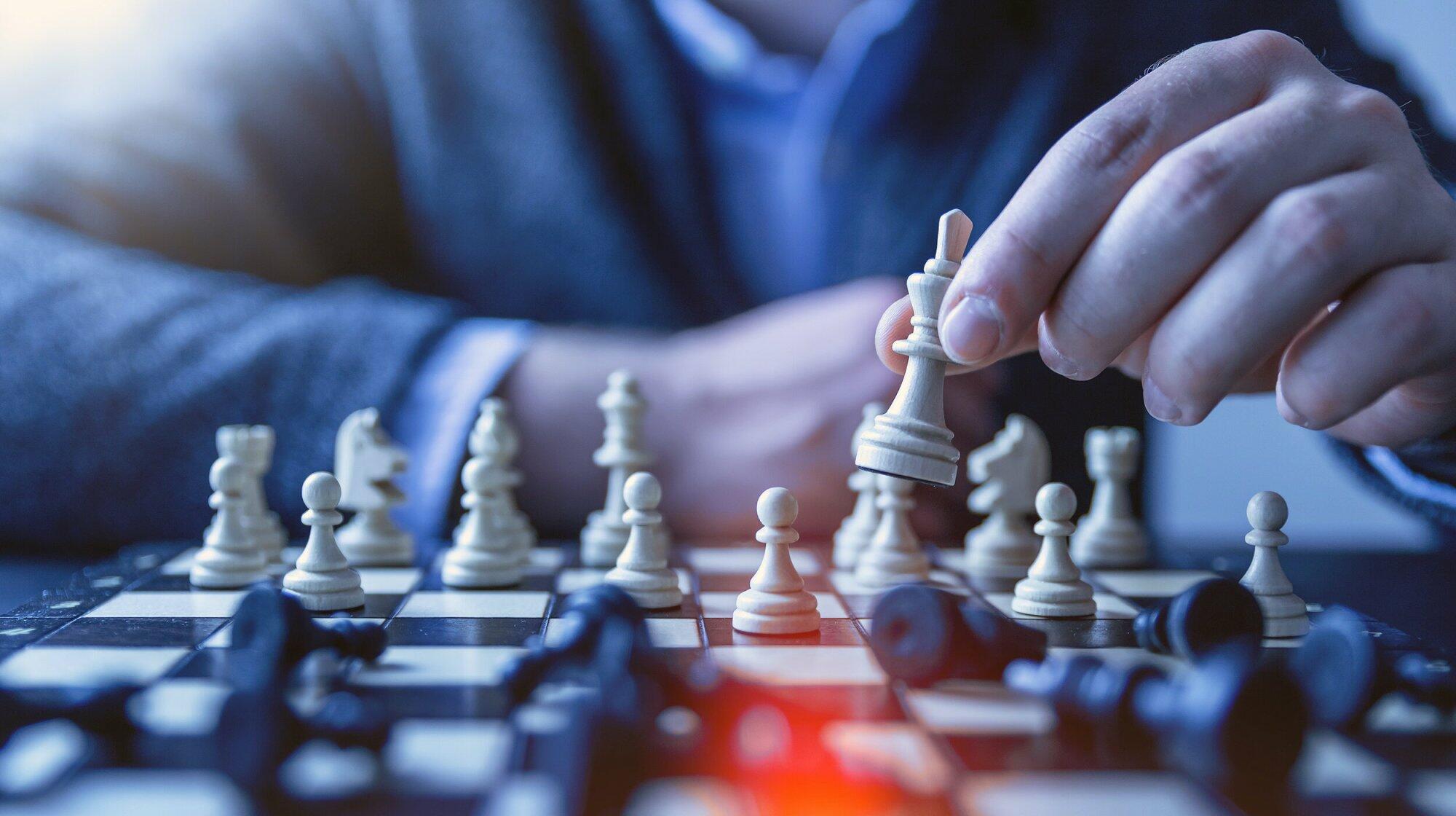 Man playing chess holding white queen